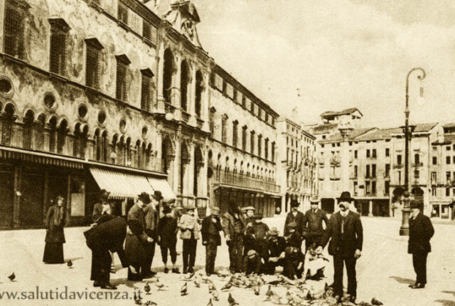 In piazza dei Signori alcuni turisti sono intenti a dar da mangiare ai colombi. Anno 1910 circa Colombi di Piazza dei Signori
